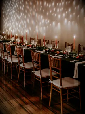 long wedding table with orange taper candles and sliced pomegranates