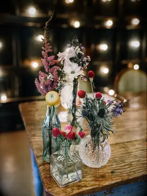 boho fall wedding centerpiece with mismatched glass jars and red, yellow and purple wildflowers