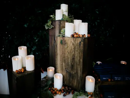 fall wedding decor idea with battery powered pillar candles and acorns on square wooden stands