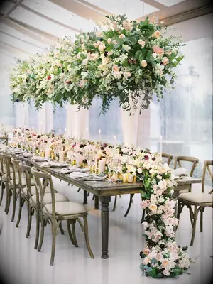 hanging wedding centerpiece with roses and greenery and matching floral table runner