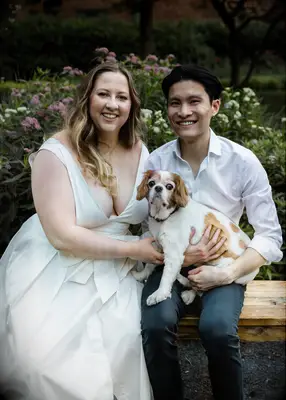 Couple posing with their dog in a park.