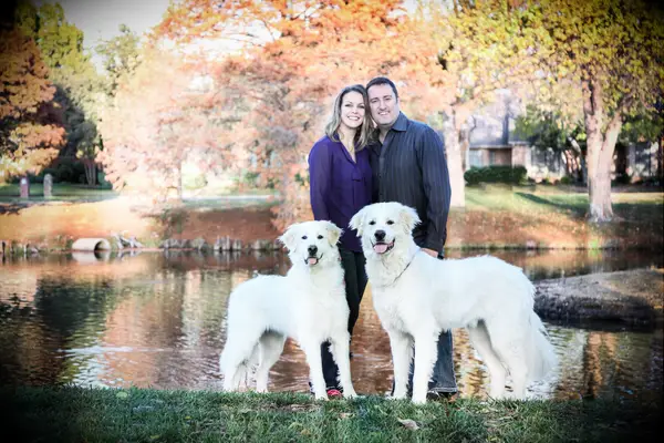 Couple posing in front of lake and autumn trees.
