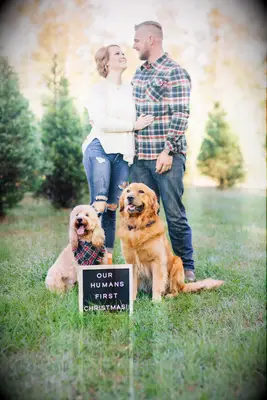 Happy couple smiling while getting their picture taken with their dogs.