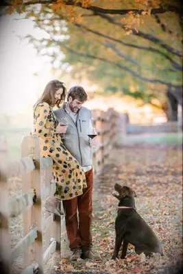 To-be-weds looking at their dog while drinking wine.