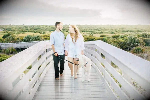Sweet couple walking barefoot with their dog.