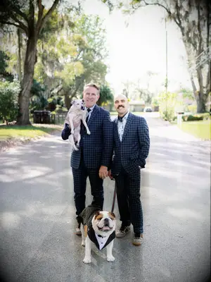 Grooms in matching suits and posing with their dogs.