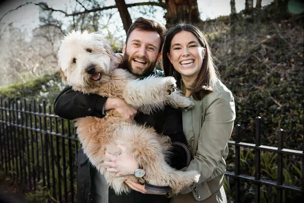 Couple smiling while holding their dog. 