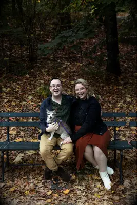 Couple smiling in the park with their small dog.