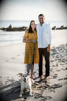 Bride and groom pose on the beach with their pooch.