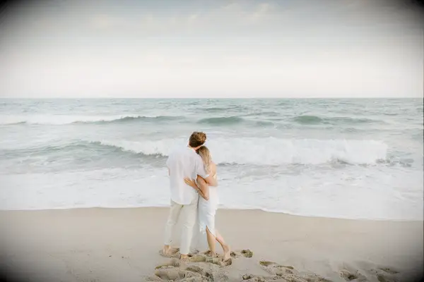Couple gazes out to sea at sunset. 