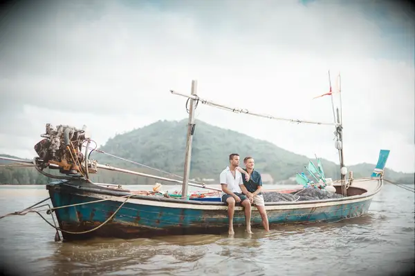 Couple sits on a long boat in Thailand. 