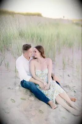 Couple cuddles in the sand on the beach. 