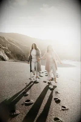 Couple walks hand in hand down the beach at sunrise. 