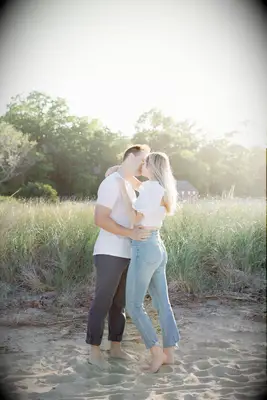 Couple kisses on the beach wearing casual clothes. 