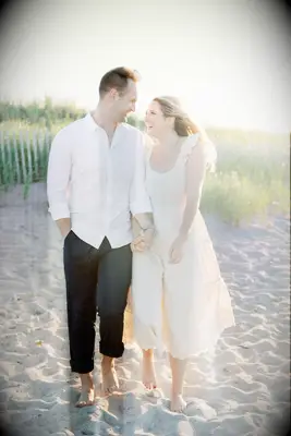 Couple looks at each other smiling on a beautiful beach. 
