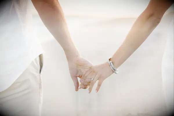 Couple holds hands on a beach. 