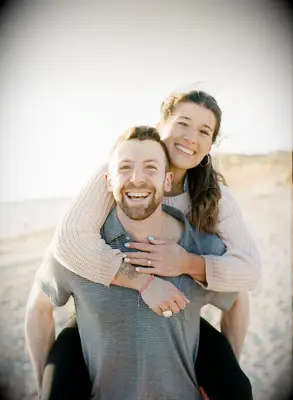 Couple poses on a sandy beach. 