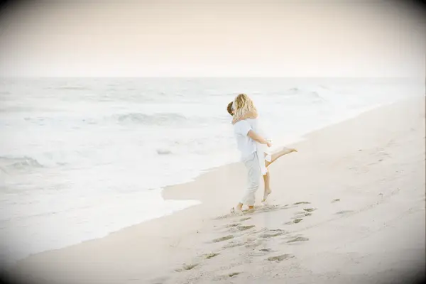 Couple embraces on a beach at sunset. 