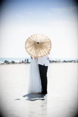 Couple embraces behind a stylish parasol. 