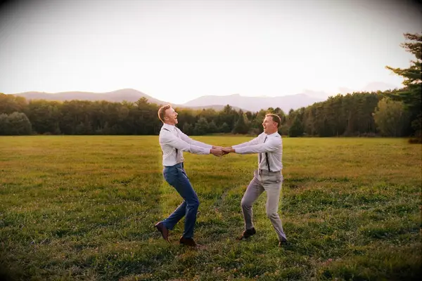 Couple twirling around in field at sunset