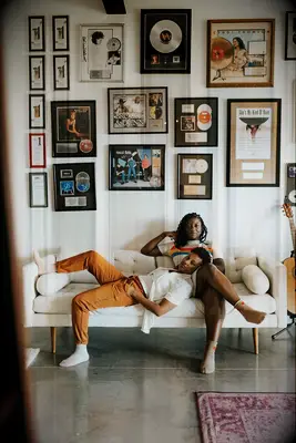 Same-sex couple relaxes on couch surrounded by vinyl records