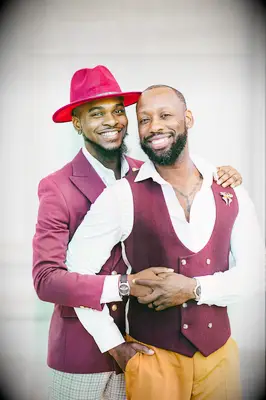 Grooms wearing burgundy suits and holding hands