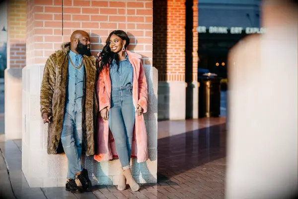 Couple smiling at each other while wearing denim outfits and coats