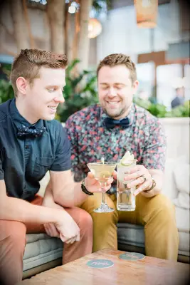 Grooms toast with craft cocktails during engagement photo shoot