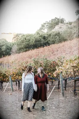 Same-sex engagement photos at vineyard during fall