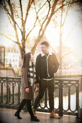 Couple walking across bridge holding hands during sunset