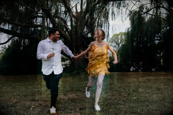 Couple holding hands and running through field