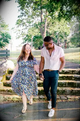 Couple walks hand-in-hand through park during sunset engagement photo shoot