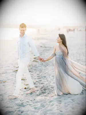 Couple walks hand-in-hand on beach during sunset