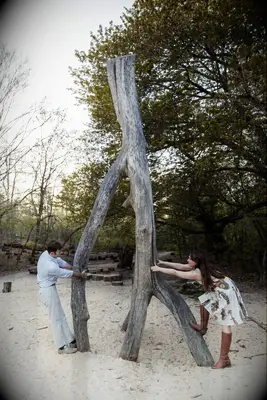 Couple pretends to break a large wishbone for an engagement photo. 