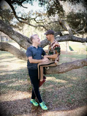 Couple poses with a tree at their local park. 