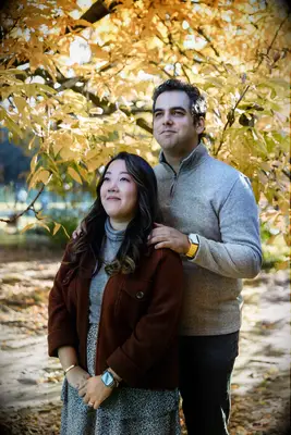 Couple stares off into the distance white their photographer snaps a photo. 