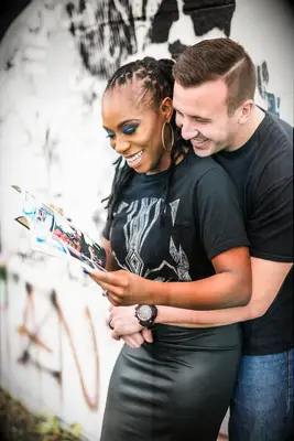 Couple smiles while flipping through a comic book together. 