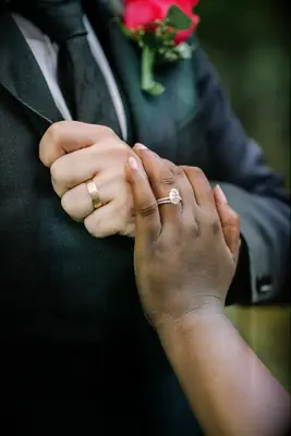 Bride wearing oval engagement ring with her hand on husband