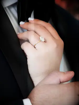 Bride wearing oval-cut engagement ring on yellow gold band