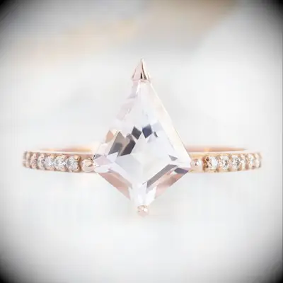 Kite shaped engagement ring with diamond clustered band