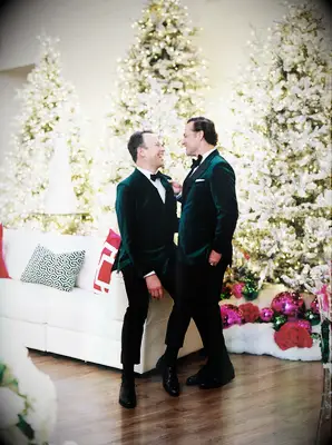 Two men in matching green velvet suits with Christmas trees in the background