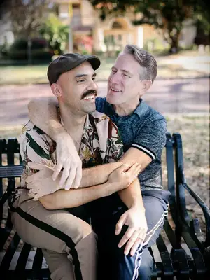 Two men sitting on a bench with their arms around each other
