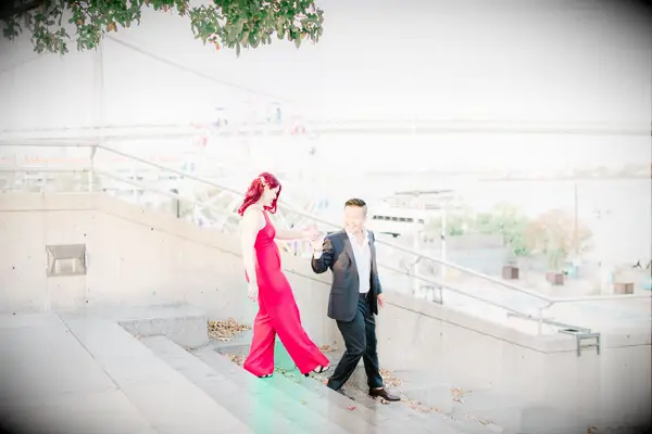 The happy newly-engaged couple take photos by a Ferris wheel