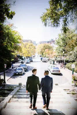 Two men hold hands as they walk down the stairs in this engagement photo
