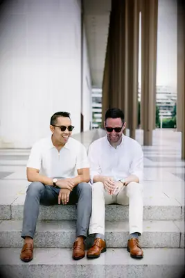 Two men wearing sunglasses smile for the camera in their engagement photo