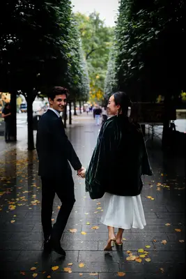 A couple walks down a tree-lined path for their engagement photo