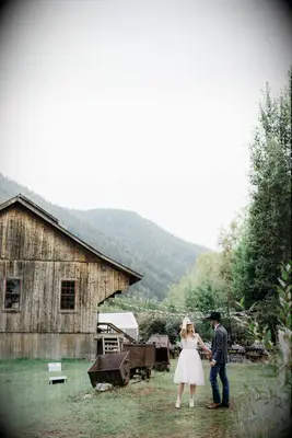 A couple stand together in the foreground of this rustic engagement photo