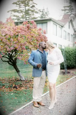A couple share a kiss outside beside an autumnal tree