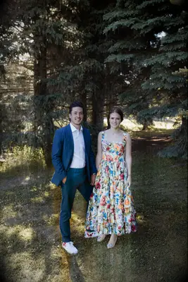 The happy couple stand together beneath the trees