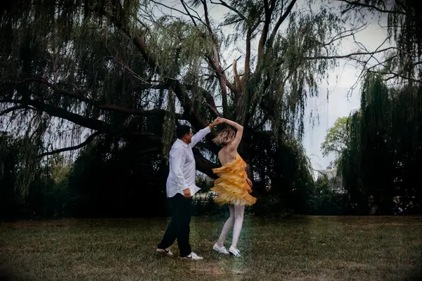 Two newly-engaged people twirl each other for their photoshoot